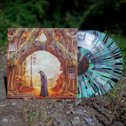 The vinyl is depicted against a background of green shrubbery with dirt below. The cover of the record is orange and brown, depicting two trees on with windows on their trunks, meeting in the middle of the frame. In between the trees is a figure in a plague doctor costume. On the bottom left corner of the cover are the words "The Dear Hunter," and on the bottom right, "Act IV: Rebirth In Reprise" in white. The vinyl record is clear with green, yellow, and black splatters.