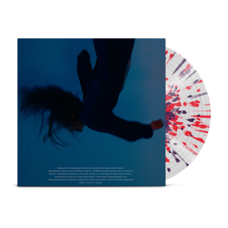 Anberlin - 'Convinced' LP. Vinyl record against a white background. The album cover is dark blue with a blurry, upside down, falling black figure with their hair flowing. There is white text below the figure. There is a vinyl record behind the album cover, which is clear with red and purple splatter.