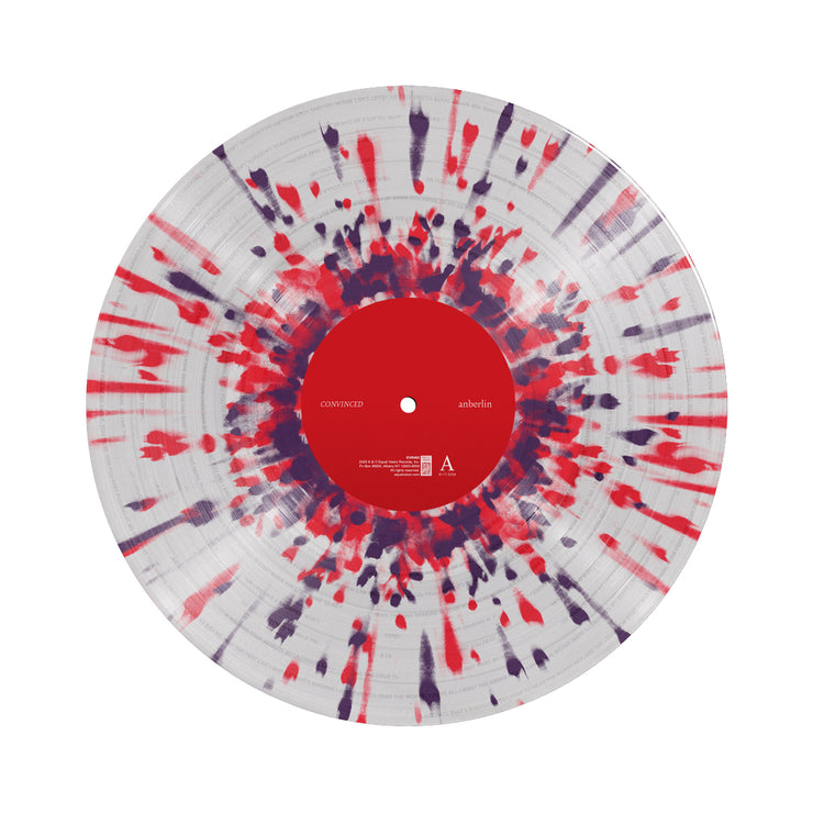 Clear vinyl against a white background with red and purple splatter. There is a red label in the center.