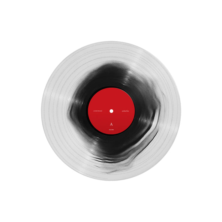 Picture of a vinyl record that is clear with black in the center. The label is red.