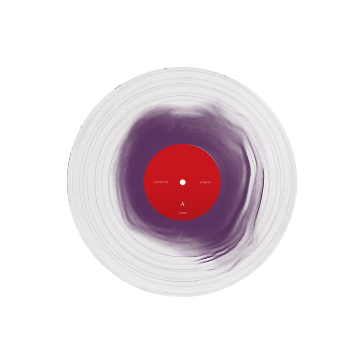A clear vinyl record with purple towards the center. The label in the center is red.