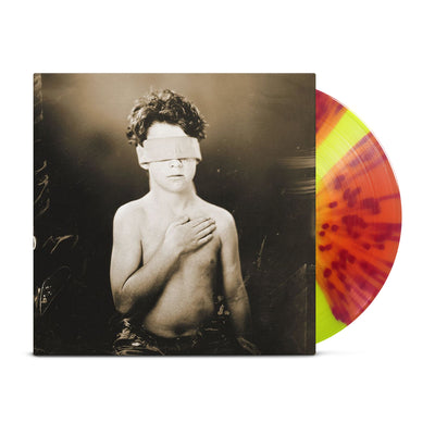 Gideon - 'Cold' vinyl. A black album cover against a white background. On the cover is the figure of a young boy in black and white with his hand over his heart. His eyes are covered by a white band. The vinyl record beside the cover is orange with red splatter.