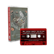 Cassette tape with artwork of a woman wearing a long grey dress in the center. The woman is reaching down onto her legs where there is a deer that has been split in half. In each corner is drawings of light pink flowers, one of them having a skull blooming out of it. On the bottom there is text that lightly says HOT WATER MUSIC and below it there is text that says FEEL THE VOID. To the right is a red cassette with the same text written on it.