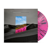 The background of this album is a gloomy black and white dune landscape.  In the middle of the album cover is a rectangle with a clear blue sky with green hills and pink flowers.  Above the rectangle reads ARMOR FOR SLEEP in white small letters and nect to it reads THE RAIN MUSEUM in black small letters.  The LP is pink with black streak patterns.