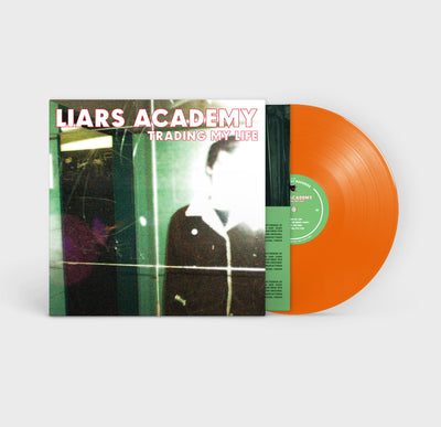 The cover of this record is a blurry photograph of a man in a dimly lit room.  Only the upper half of the mans body is showing, and his face is blocked out by the lens flare of the camera.  The vinyl itself is bright orange with a green center.