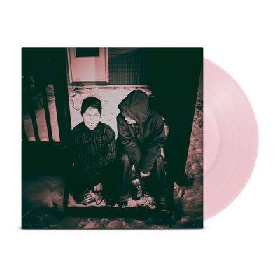 Square vinyl with a pink and white image of two people sitting on a porch that leads to a doorstep. There is a  vinyl record that is sticking out of the vinyl cover that is the color bubblegum pink.  