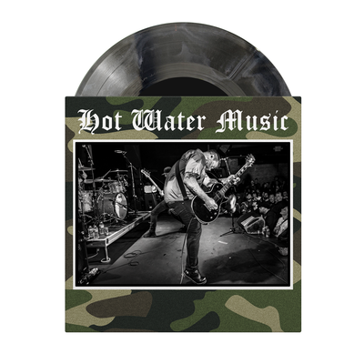 Camo vinyl cover that shows a black and white image of a guitarist on it.  A black and white mix vinyl is sticking out the top of the case.