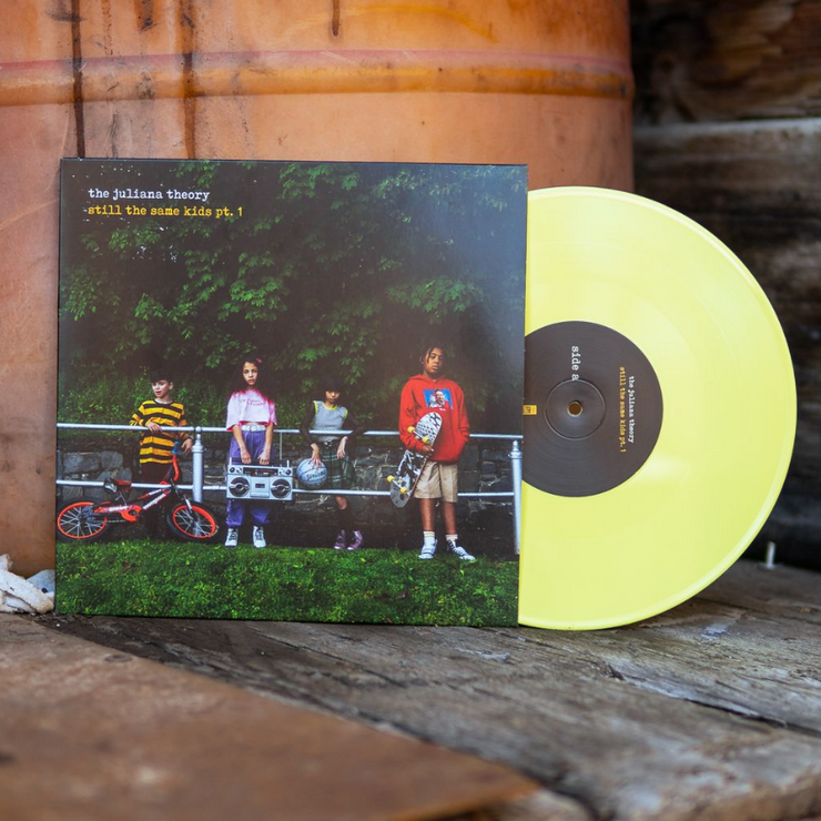 Vinyl jacket with an image of four kids leaning against a railing and holding helmets, skateboards, bikes, and a boombox. There is small text in the top left corner that says THE JULIANA THEORY. Under that there is yellow text that says STILL THE SAME KIDS PT. 1. Peeking out of the side is a yellow vinyl.