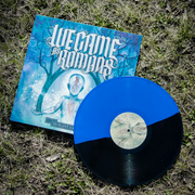 The vinyl  has a light blue background. In the middle of the cover is a faceless figure that is also light blue, with its arms extended and brown trees growing out of its hands. The trees start to converge towards the top of the album. The words WE CAME AS ROMANS read above the figures head in large letters. Below the figure reads TO PLANT A SEED in small letters.  There is a vinyl laying on top of the vinyl cover that is colored Opaque Blue and Black Split.  All of this is on the grassy ground.