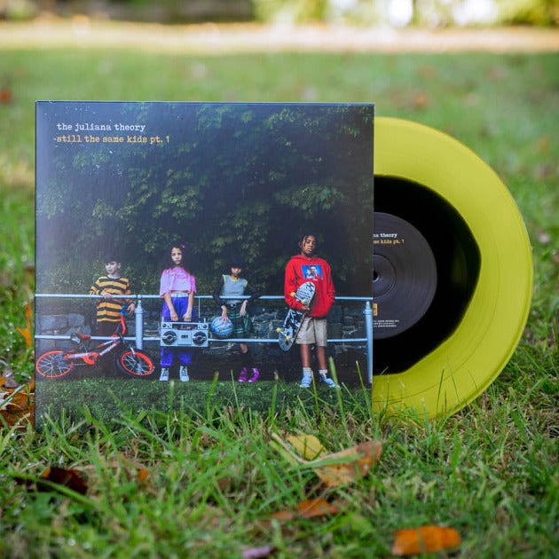 Vinyl jacket with an image of four kids leaning against a railing and holding helmets, skateboards, bikes, and a boombox. There is small text in the top left corner that says THE JULIANA THEORY. Under that there is yellow text that says STILL THE SAME KIDS PT. 1. Peeking out of the side is a black and yellow vinyl.