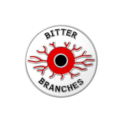 A pin made to look like a blood shot eyeball with text on it that reads BITTER BRANCHES.