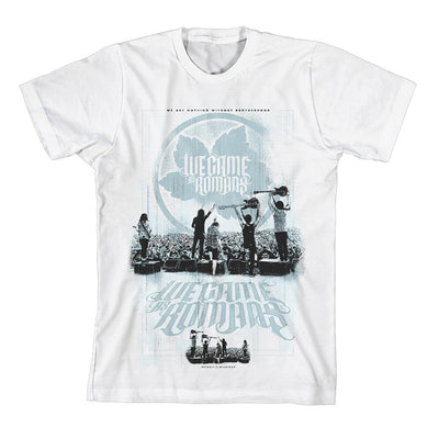 White short sleeve shirt with an image of an outdoor concert being played in black and white. Above the image is WE CAME AS ROMANS written over a blue leaf. Below the band playing, WE CAME AS ROMANS is written again in blue font. Below the blue font is the same image from the show, but it is much smaller and mirrored.