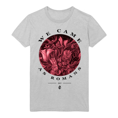 Heather grey short sleeve shirt with a circle design in the center. Inside the circle is a red floral design. Around the circle is text that says WE CAME AS ROMANS in black. Below that is text that says 2015, with a black horizontal line on either side. Below that is a letter C with two crosses through it.