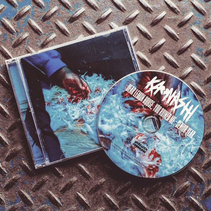 Square CD with an image of a person laying on the ground with their hand covered in blood. Surrounding their hand are white feathers, some covered in blood. All of this is on light wooden flooring. Next to he cover is a disc with the same image on it, with KAONASHI written on top in scratchy white font. Below that is white text that says DEAR LEMON HOUSE, YOUR RUINED ME: SENIOR YEAR. 