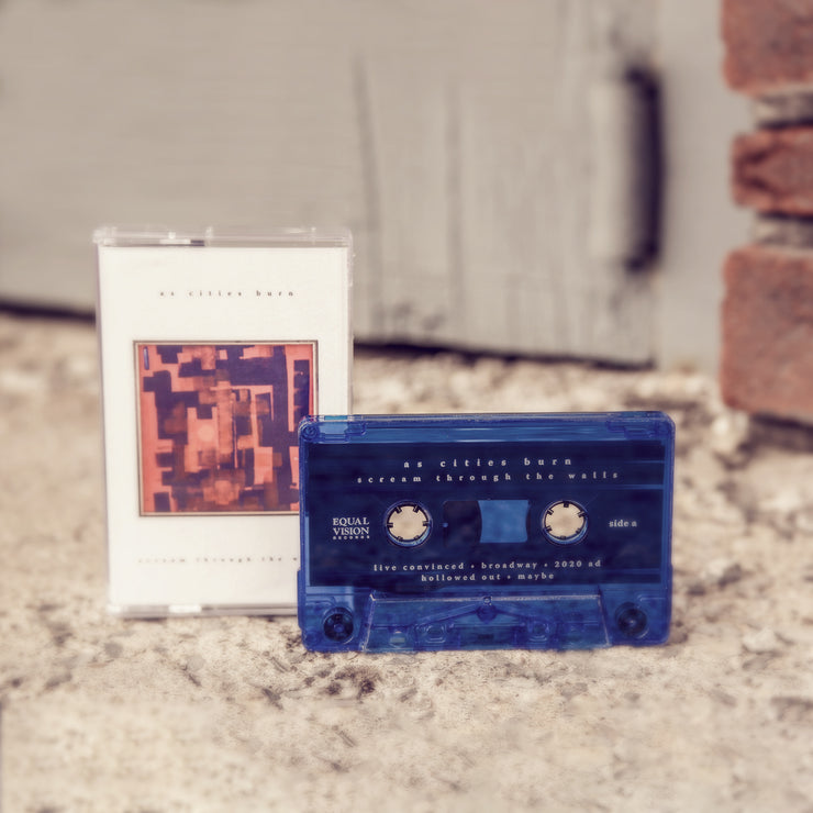 Cassette with black text that says AS CITIES BURN at the top. below that is a painting with a red background and thick blue paint brush like strokes in it. Below that there more black text that says SCREAM THROUGH THE WALLS. To the right of the cover is a blue cassette tape. Both are sitting on top of asphalt.